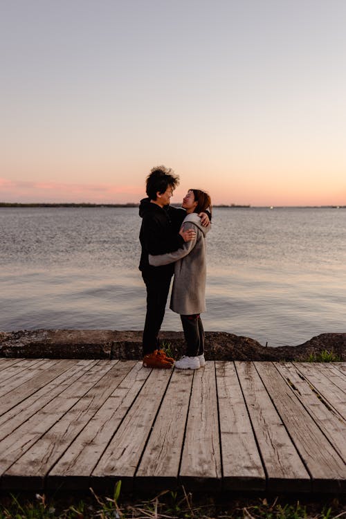 Couple Standing on Wooden Dock during Sunset
