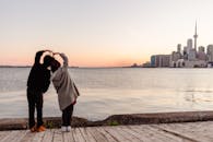 Faceless couple forming heart with hands and enjoying Toronto view
