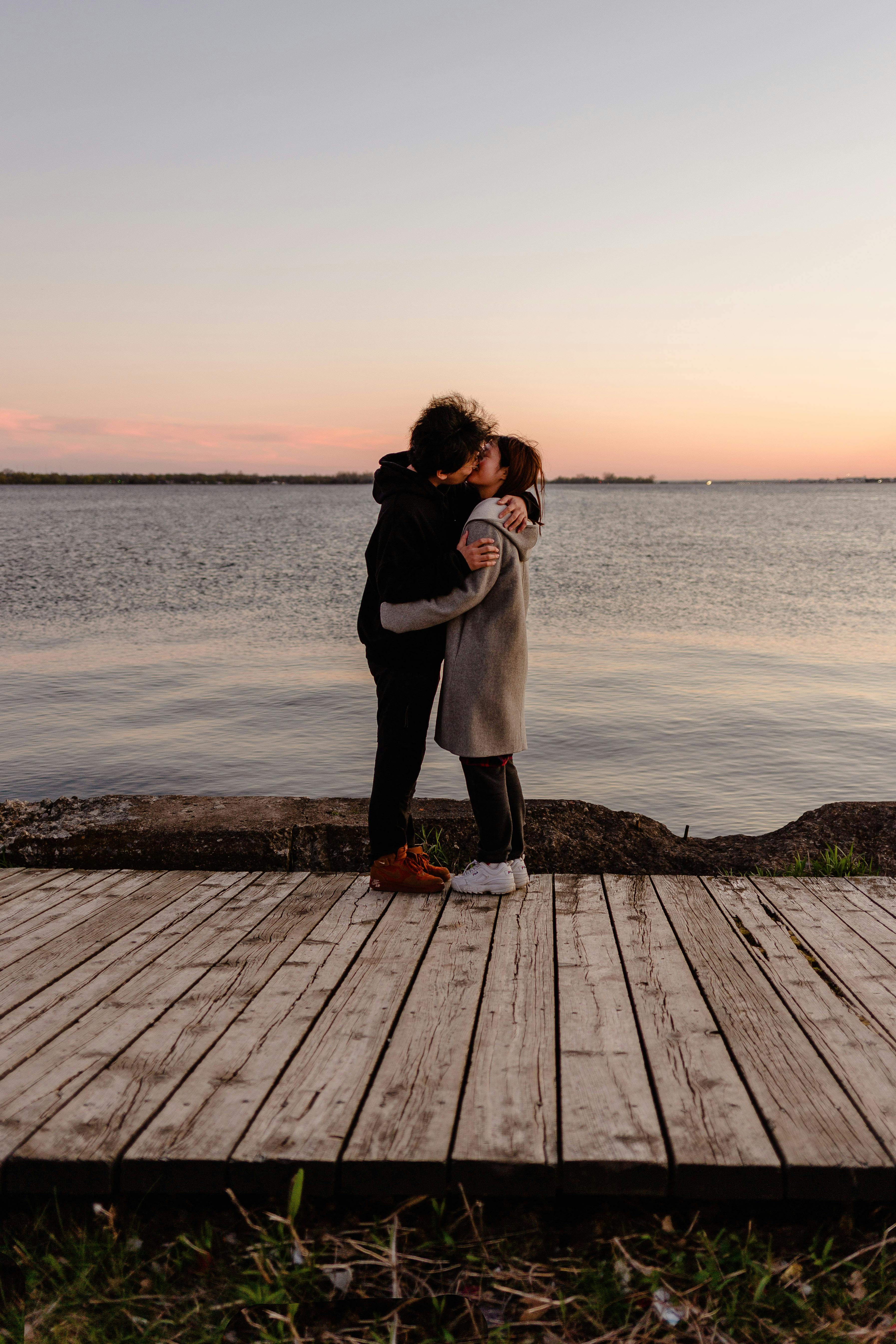 Image of Couple kissing on a dock at sunset