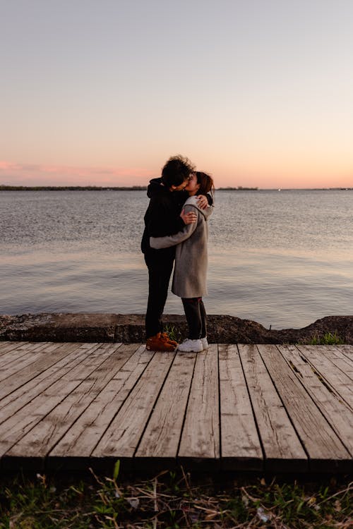 Couple Kissing while Standing on Wooden Dock
