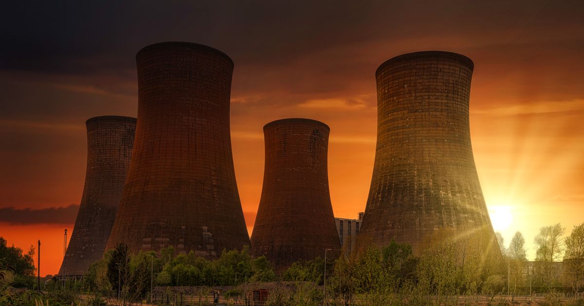 Power plant cooling towers silhouetted against a sunset.