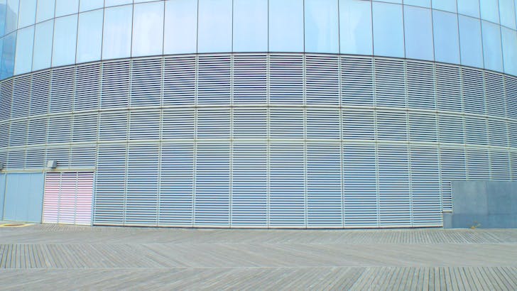 Contemporary glass building wall with aluminum solar facade shading panels on clear sunny day