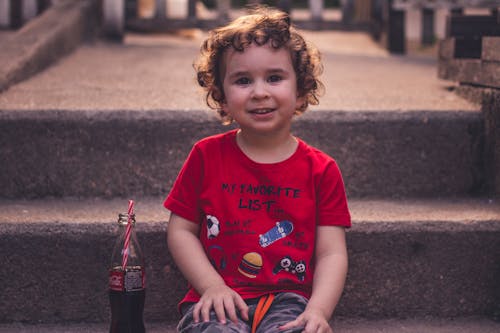 Free Kid in Red Crew Neck T-shirt Sitting on the Stairs Stock Photo