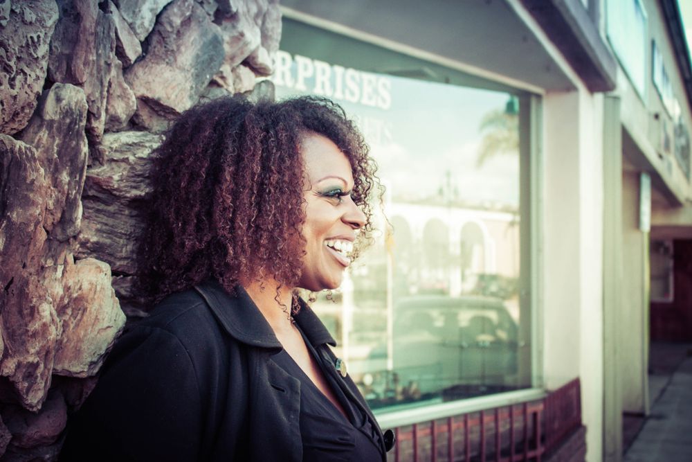 A woman laughing outside a shop window