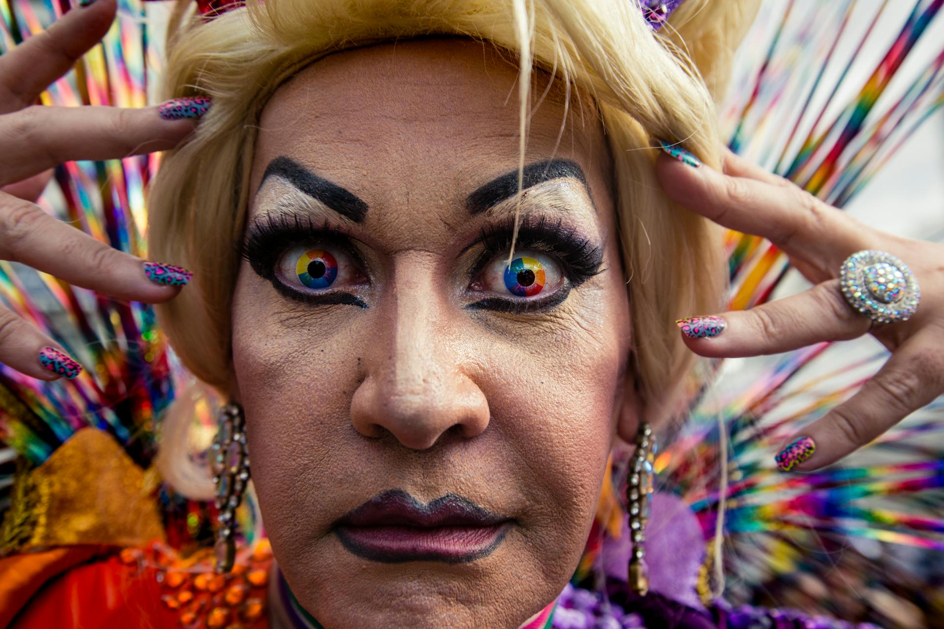 Colorful drag queen poses with rainbow contact lenses at São Paulo Pride Parade.