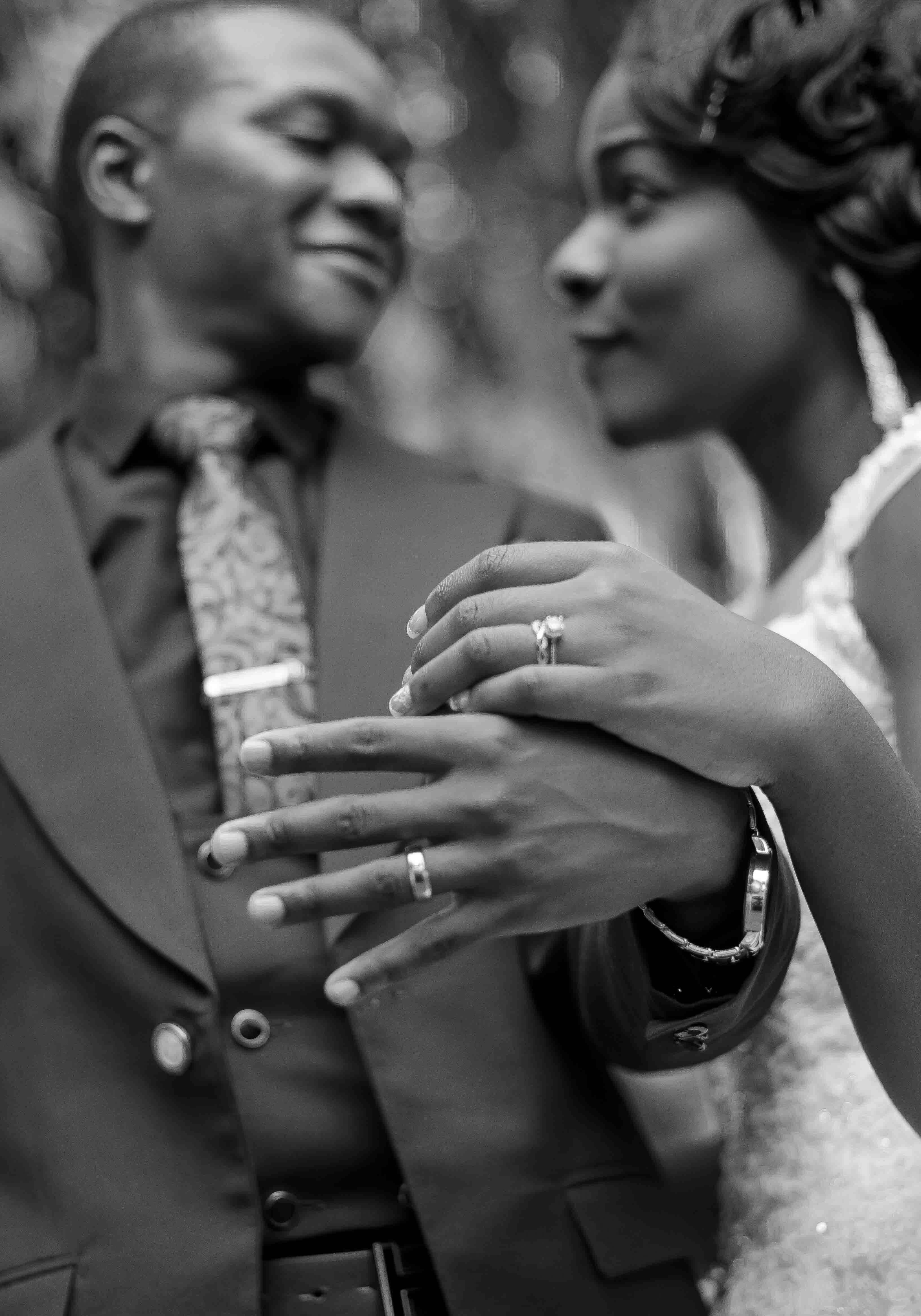 Romantic grayscale portrait of a newlywed couple showcasing their wedding rings and love.