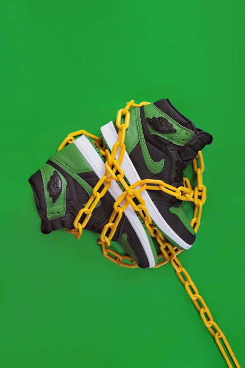 Stylish sporty boots chained on green surface