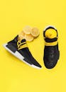 一双时尚黑色运动鞋的顶视图，白色外底放在黄色表面上，旁边搭配新鲜的天然柠檬