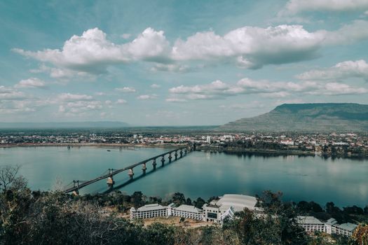 A picturesque bridge spans the Mekong River in a tranquil Laotian landscape.