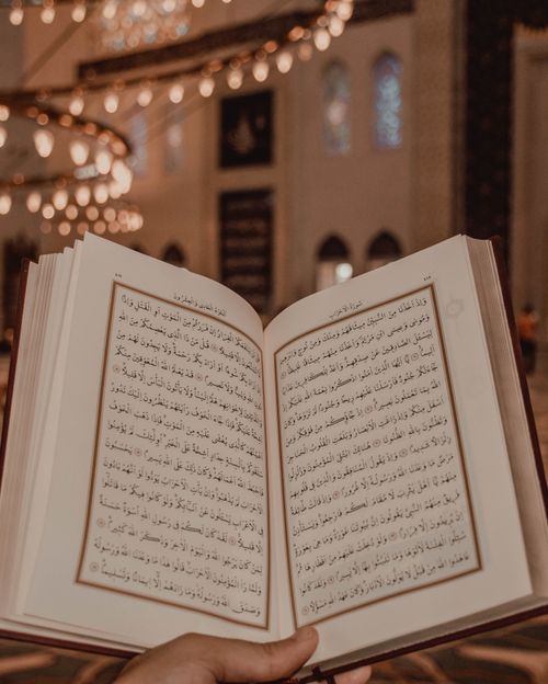 Free Anonymous person taking ancient Islam scripture in book format in Arabic language in old mosque in hand while spending vacation in Eastern country Stock Photo