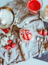 Top view of delicious sweat dessert served with strawberry and meringue on napkin with tea spoons and glass of strawberry fresh