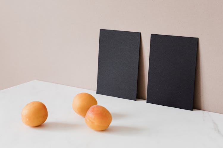 Creative Arrangement Of Two Black Cardboard Cards And Ripe Apricots