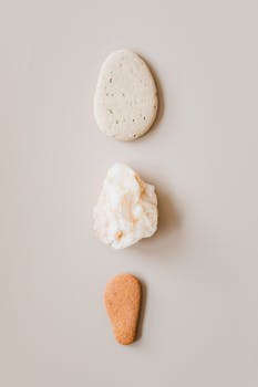 A minimalist display of three natural stones arranged on a neutral background.