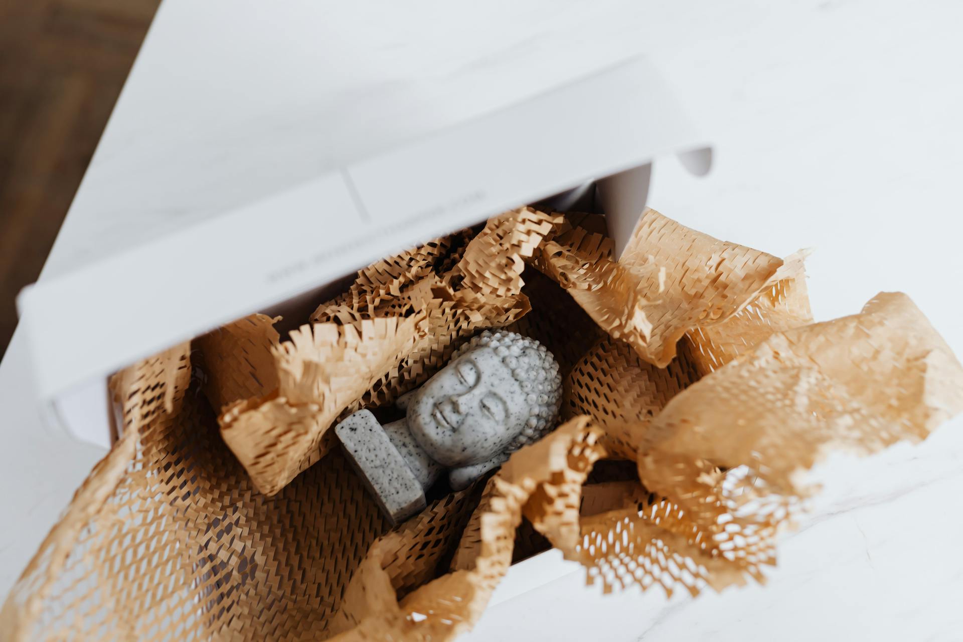 Granite Buddha bust packaged for delivery, nestled in protective material.