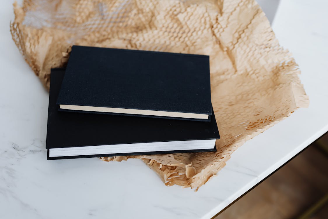 Closed black notebooks and packing material · Free Stock Photo