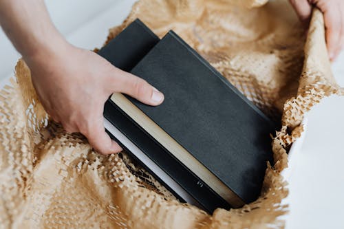 Anonymous man preparing notebooks for sending by post