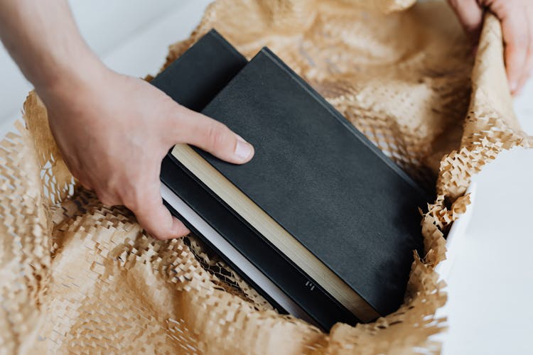 Anonymous Man Preparing Notebooks For Sending By Post