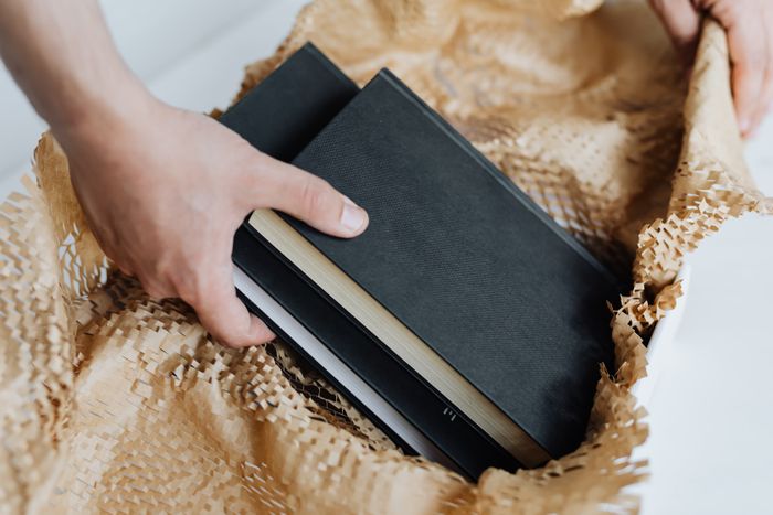 Hands carefully packing books into a shipping box