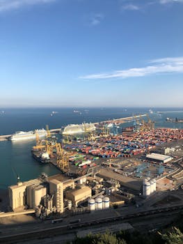 From above of modern loading harbor with cargo and infrastructure and seascape with ships floating on water in sunny day