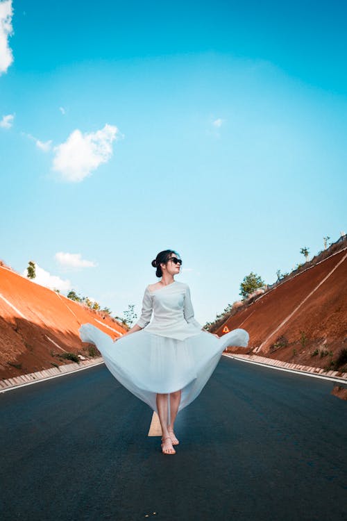 Free Woman in white dress walking along road Stock Photo
