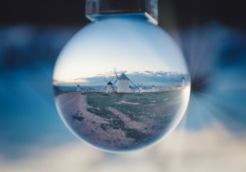 Artistic glass ball reflection capturing iconic windmills in Campo de Criptana, Spain at dusk.