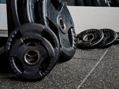 Detailed image of black weight plates stacked in a gym setting, perfect for fitness and workout themes.
