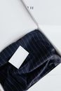 From above of stylish black striped silk dress with white visit card mockup placed in white carton box after receiving mail delivery of online order