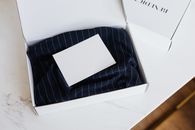 大理石桌上放着一个极简主义的白色盒子，里面装着衣服和空白卡片，非常适合品牌推广
