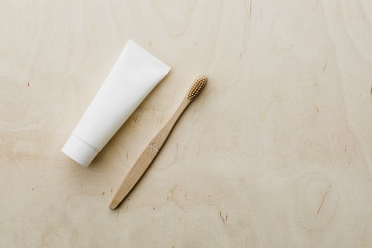 White Tube And Bamboo Brush On Wooden Table