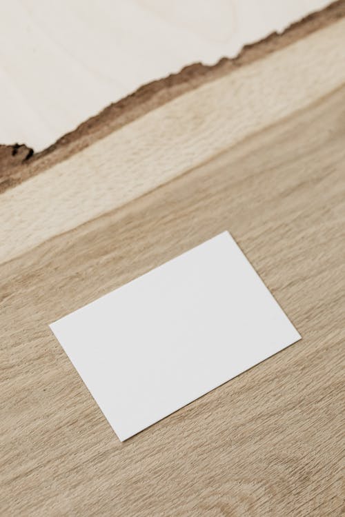 Empty white business card on wooden desk