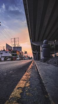 From below of houses and cars on asphalt road on city street at sunset