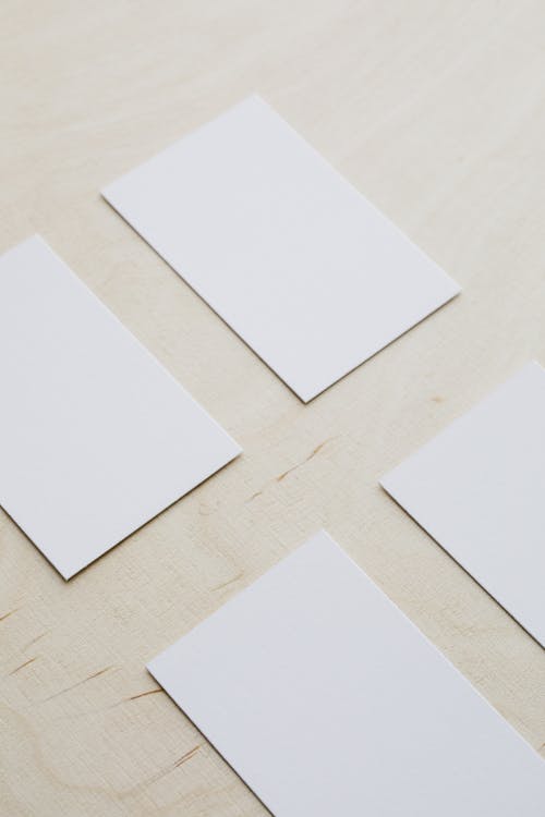 From above of white mockup rectangular visiting cards arranged neatly on wooden table