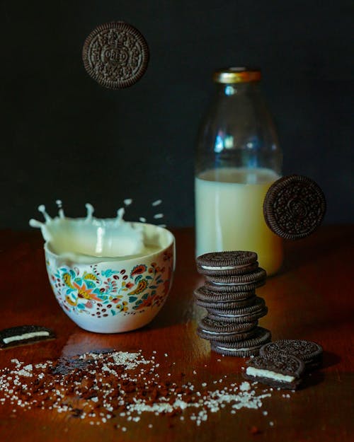Free Composition of tasty chocolate biscuit stacked on table near milk jar and falling into ceramic bowl with fresh milk Stock Photo