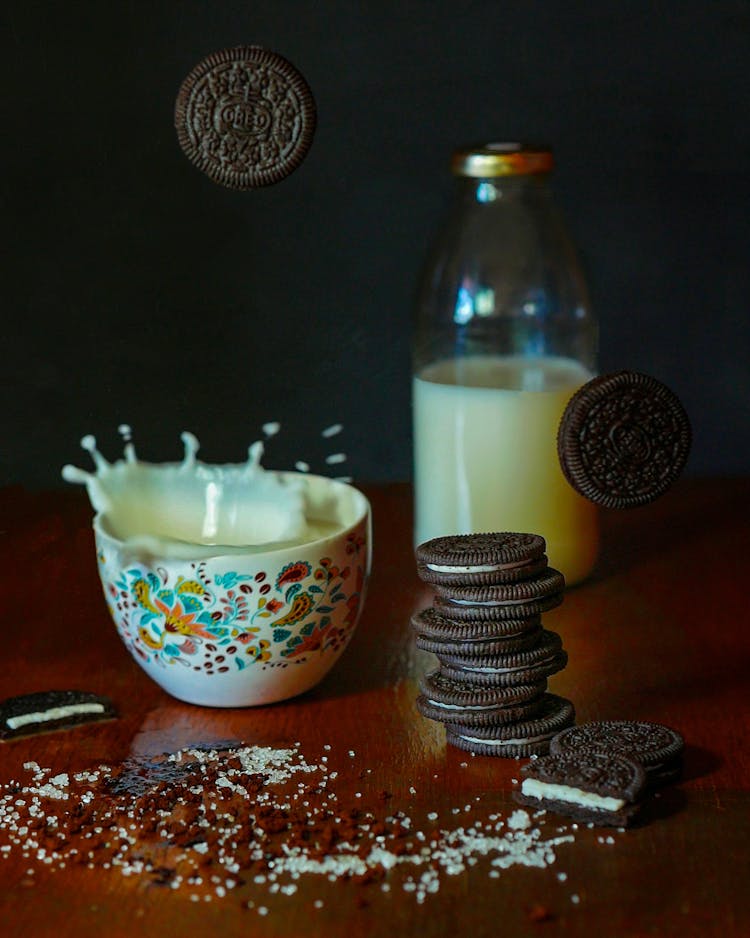 Chocolate Cookies Falling Into Bowl With Milk