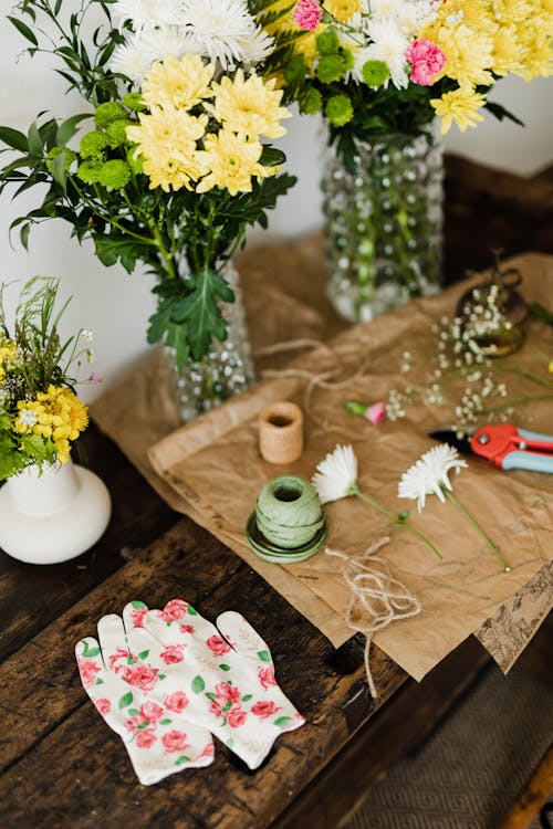 Free From above of fresh chrysanthemum bouquets in vases and floristry tools on wooden bench at florist shop Stock Photo