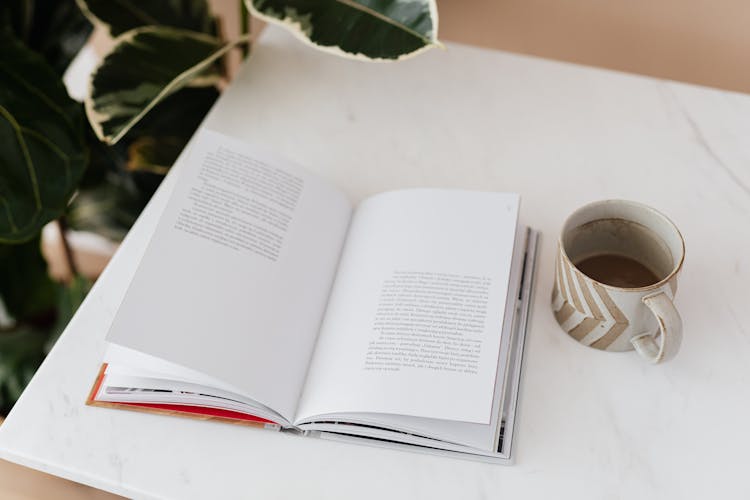 Open Book And Cup Of Coffee On Table