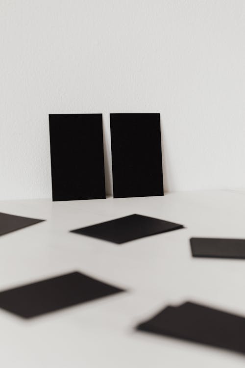 Free Collection of black mockup business cards placed against white wall and scattered on white surface Stock Photo