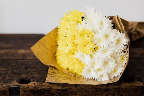Elegant bouquet of yellow and white mum flowers on dark brown lumber table