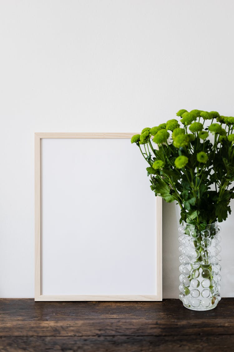 Blank Picture In Wooden Frame And Flowers In Vase