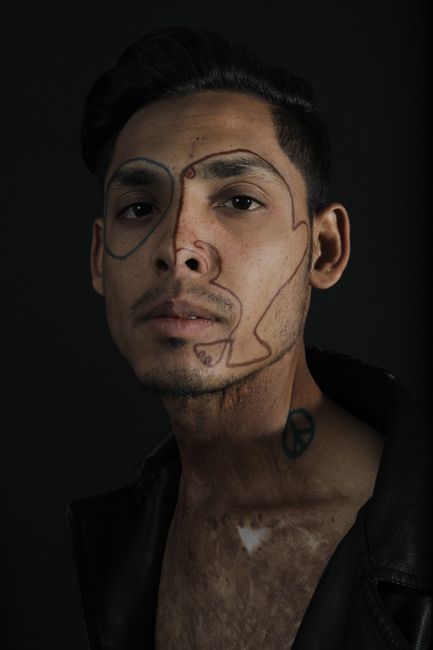 A man with artistic face drawing, captivating expression on dark background.