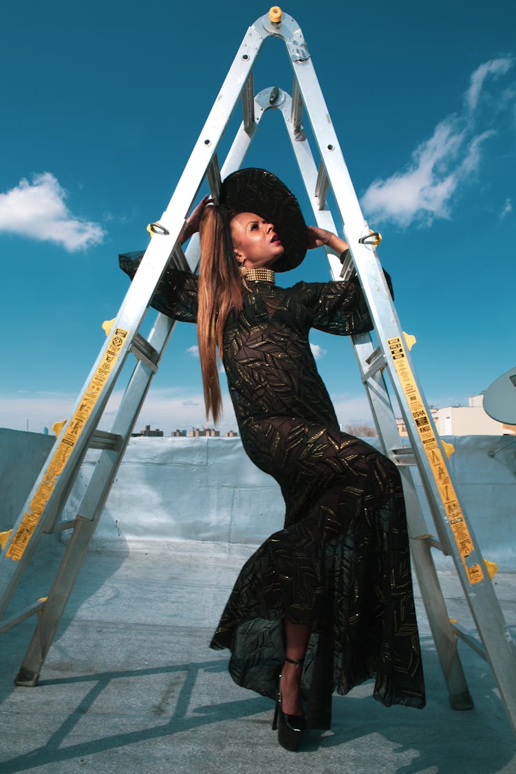 A Woman In Black Dress Posing Under The Ladder