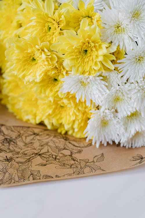Closeup of bouquet of various fresh flowers placed on flower packaging white table