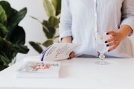 Anonymous woman reading book and standing near table