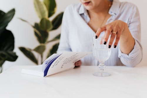 Woman with glass of water reading book