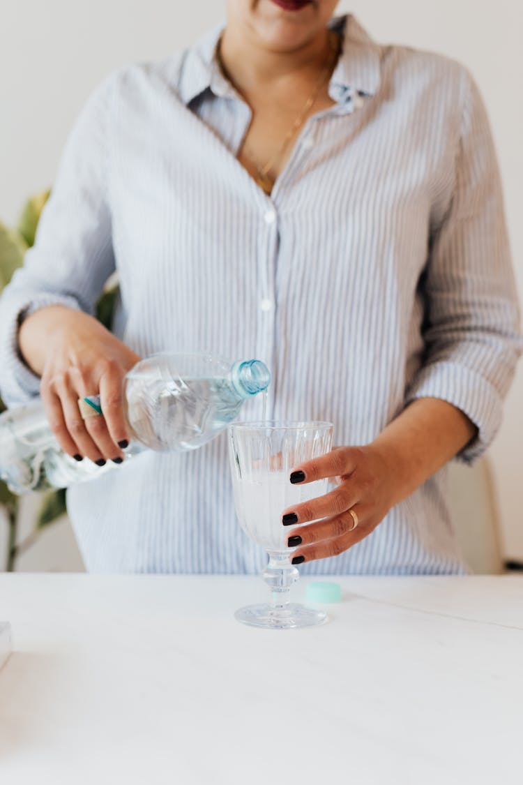 Crop Woman Pouring Water Into Glass