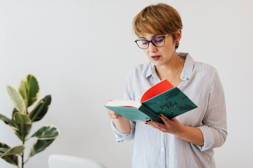 Smart woman in eyeglasses reading book