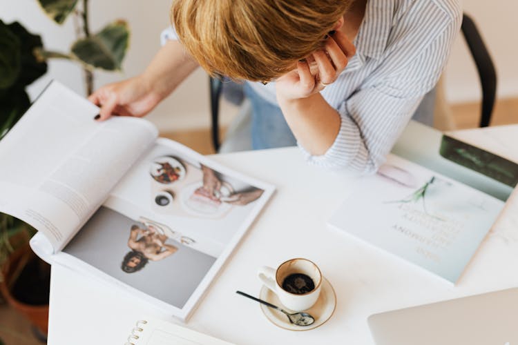 Crop Woman Reading Journal At Desk