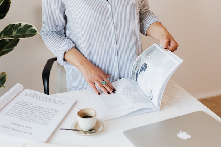 Crop Woman Reading Professional Magazine In Workspace