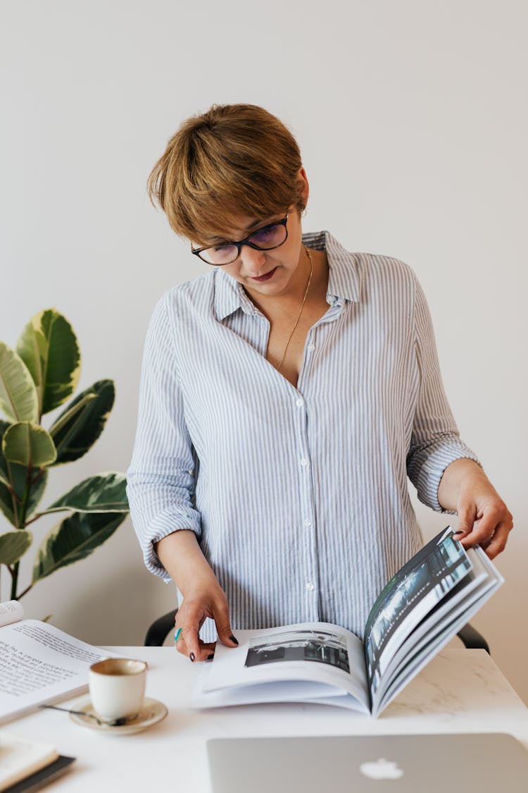 Woman Reading Professional Magazine In Workspace