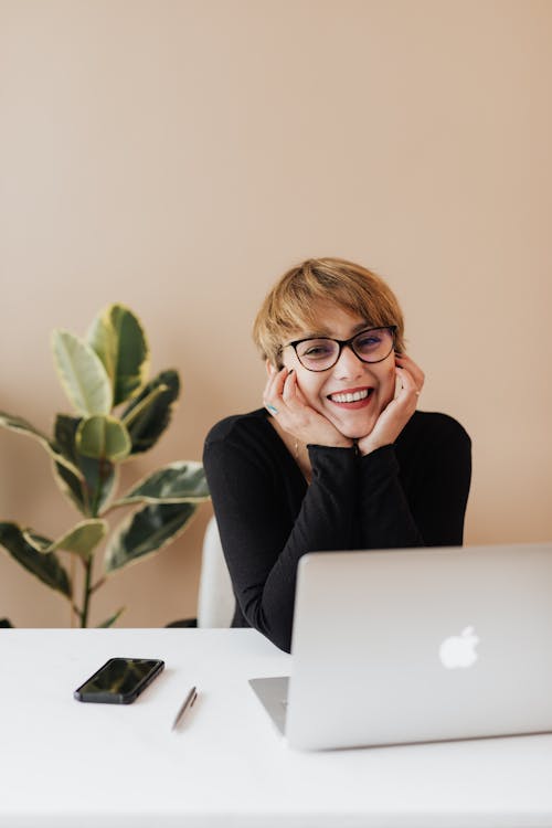 Free Cheerful woman smiling while sitting at table with laptop Stock Photo